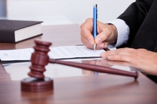 Gavel sits on a desk, while a judge takes notes